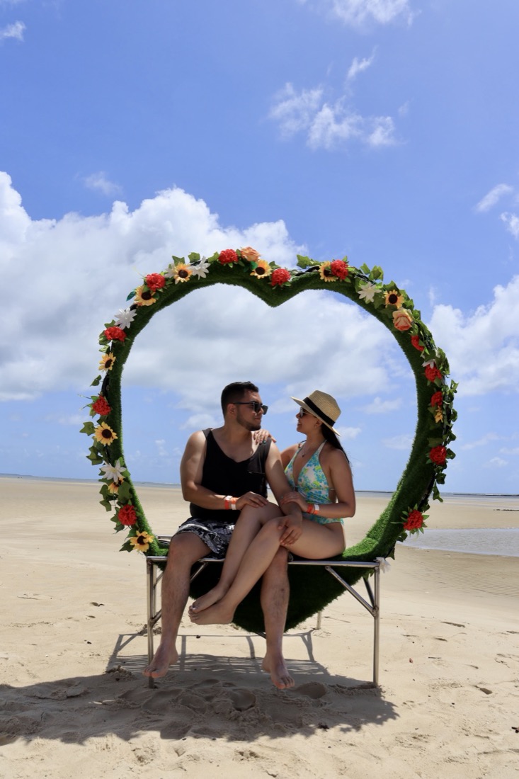 Kharen y Camilo en la playa, dentro de un corazón de flores